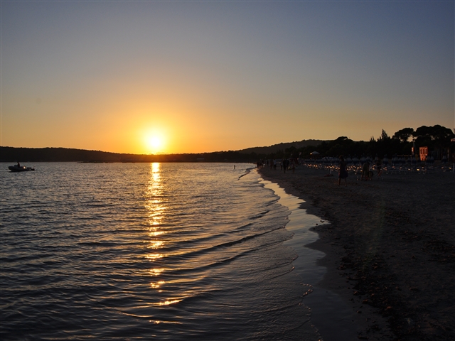 Il sole che tramonta lascia la scia arancione nel mare increspato.